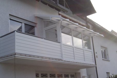 Weißer Balkon mit Überdachung an einem modernen Haus.