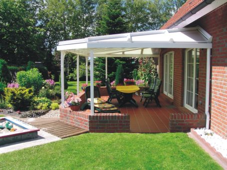 Terrasse mit Überdachung, Gartenmöbeln und bunten Blumenbeeten.