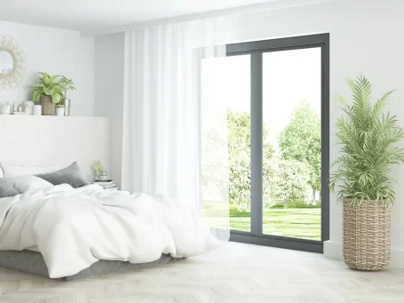 Helles Schlafzimmer mit einem Bett, großen Fenstern und einer Pflanze in einem Korb.