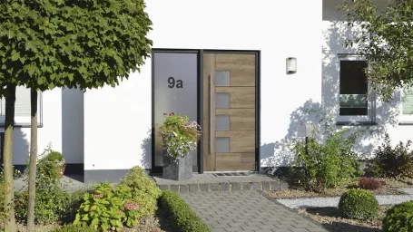 Holztür mit verschiedenen Fenstern, umgeben von Pflanzen und einem gepflegten Gehweg.