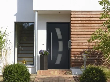 Moderne Haustür in Anthrazit, umgeben von Holzverkleidung und grünen Pflanzen.
