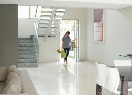 Eine Person tritt in einen modernen Raum mit Treppe und hellen Wänden ein.